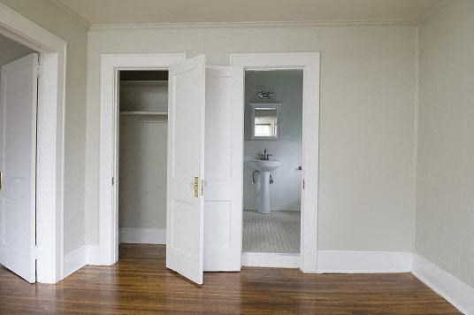 an empty room with three doors and a bathroom