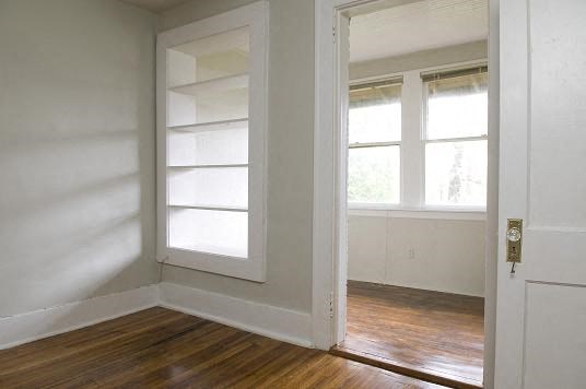 an empty room with a door and two windows