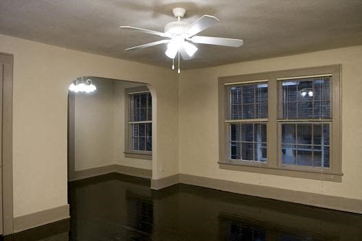 an empty room with a ceiling fan and two windows