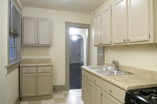 an empty kitchen with white cabinets and a sink