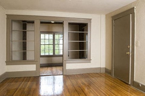 an empty living room with a door and a window