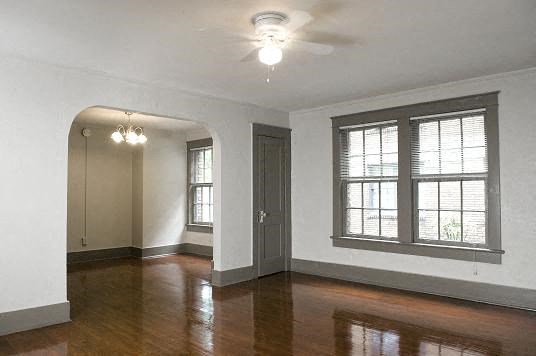 an empty living room with a ceiling fan and windows