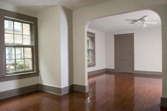 an empty living room with a ceiling fan and a door