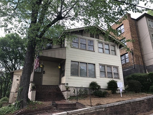 a white house with an flag in front of a tree