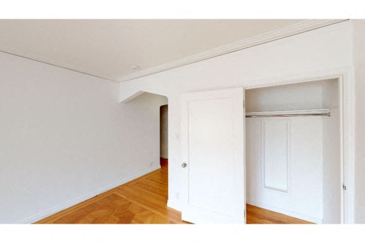 an empty room with a white door and a wood floor