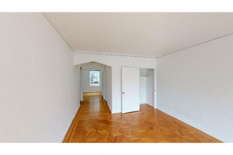 a hallway with a wood floor and white walls