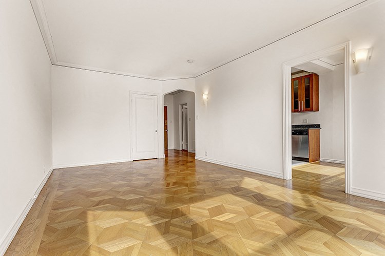 a renovated living room with a wooden floor and white walls