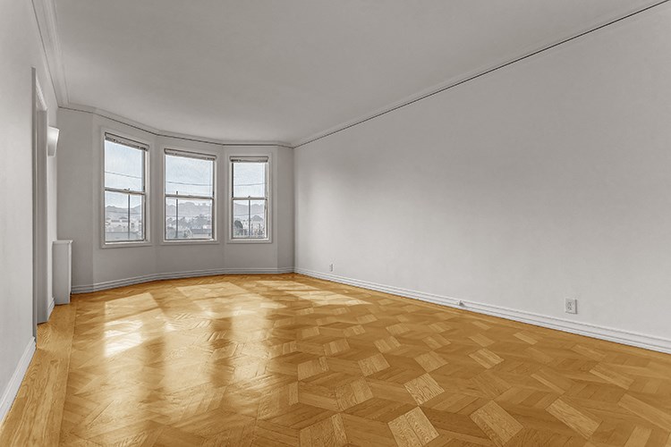 an empty living room with wood flooring and a window