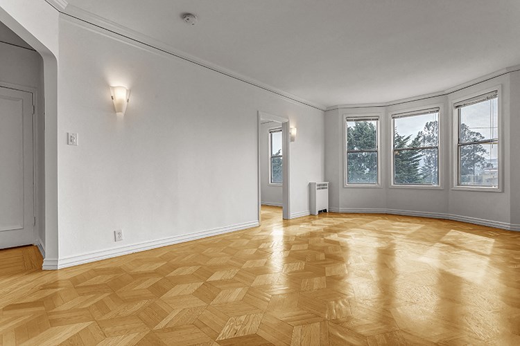 an empty living room with wood flooring and windows
