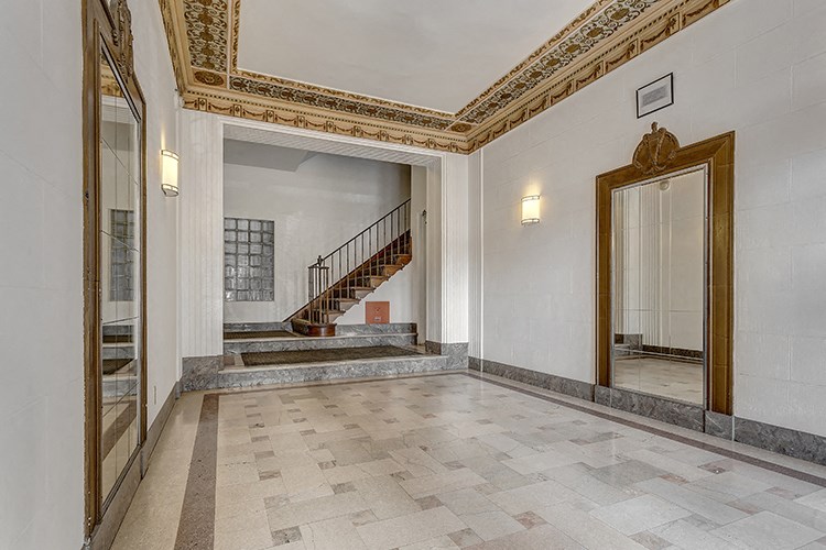 the lobby of a building with a staircase and a mirror