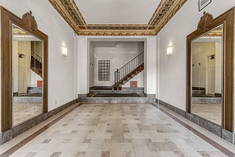 a large hallway with three mirrors and a staircase in a building