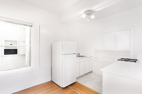 a white kitchen with a refrigerator and a window