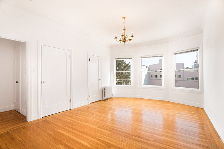 an empty living room with a wood floor and a chandelier