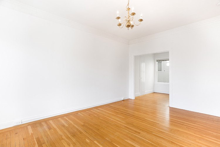 a empty living room with a wooden floor and a chandelier