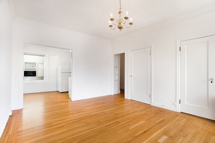 a empty living room with a wood floor and a chandelier