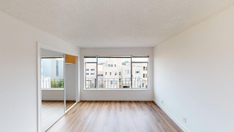 an empty living room with wood floors and a large window