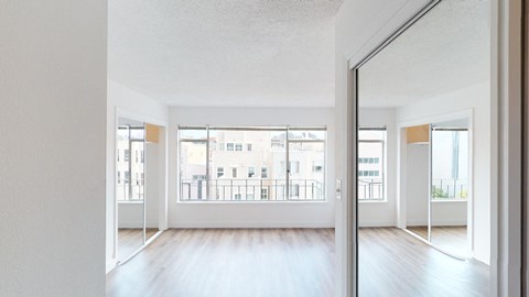an empty living room with wood floors and a large window
