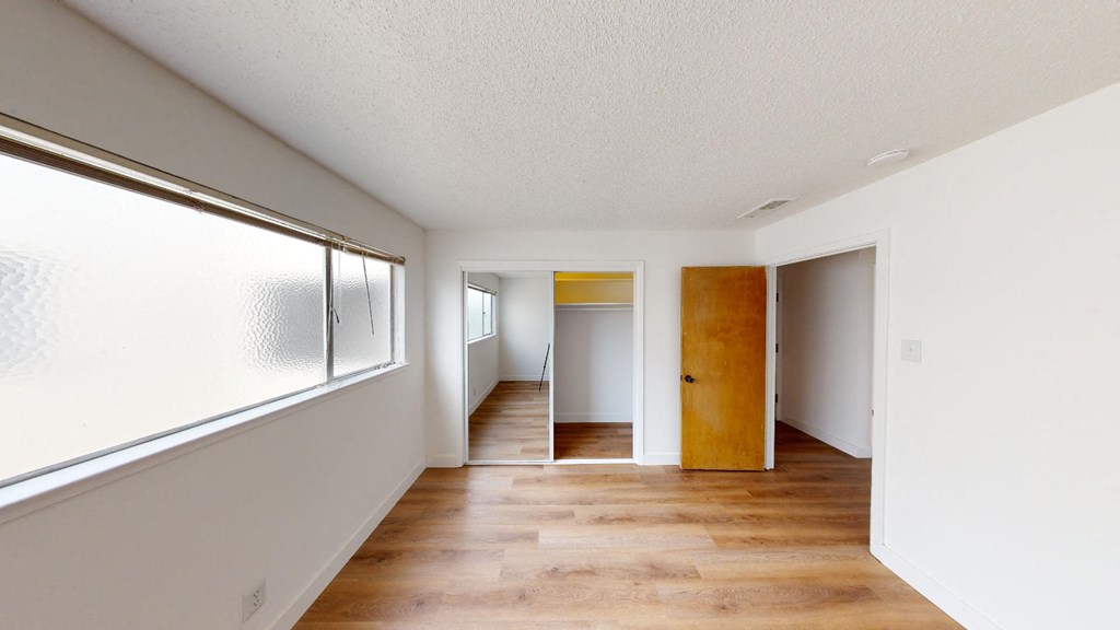 a living room and hallway with a wood floor and a window