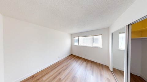 an empty living room with wood floors and a mirrored closet