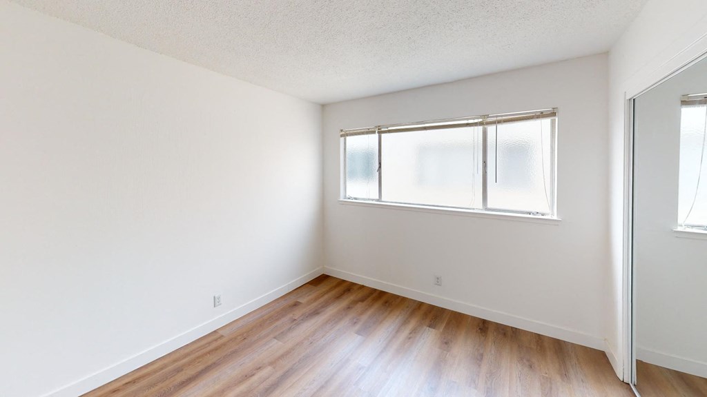 an empty room with wood floors and a window