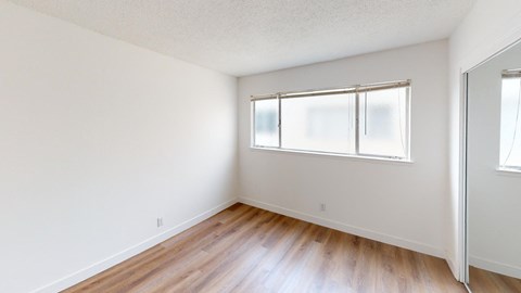 an empty room with wood floors and a window