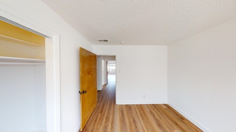 an empty room with a wooden floor and a door to a hallway