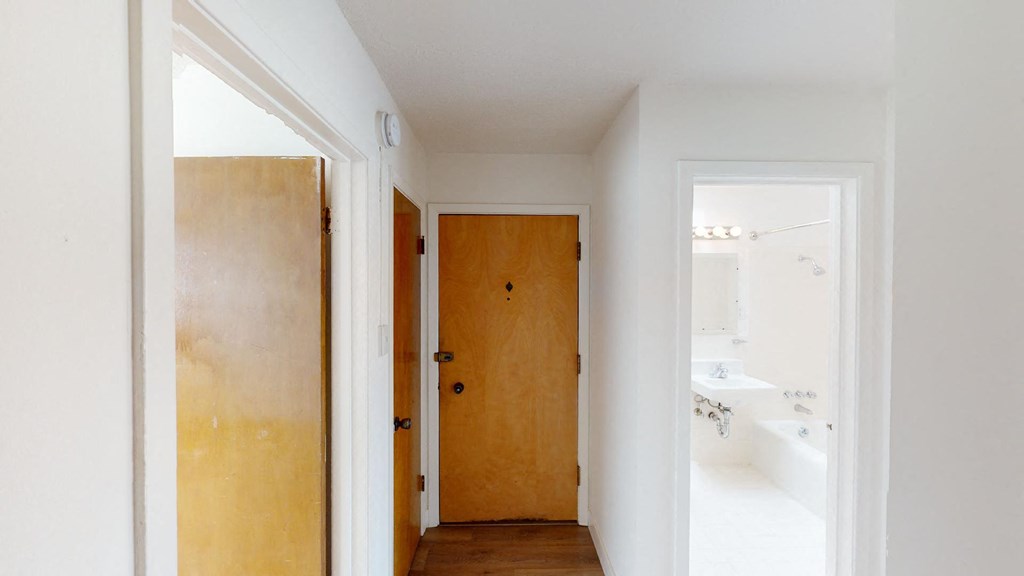 a hallway with a wooden door and a white bathroom