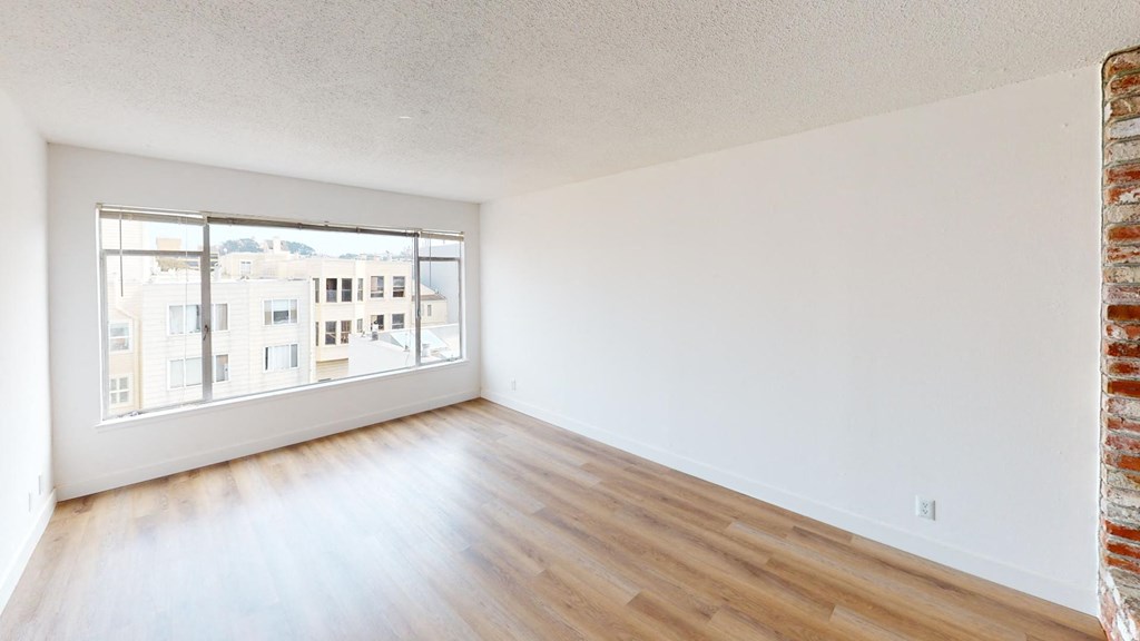 an empty living room with wood floors and a window