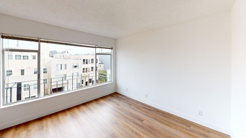 an empty living room with a large window and wooden floors