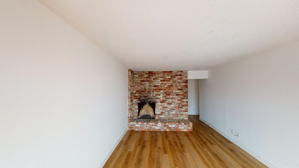 a living room with a brick fireplace and wooden floors