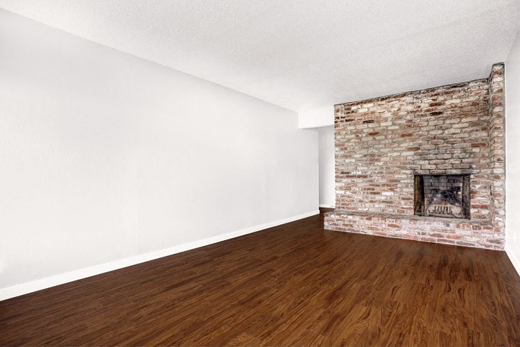 an empty room with a brick fireplace and wooden floors