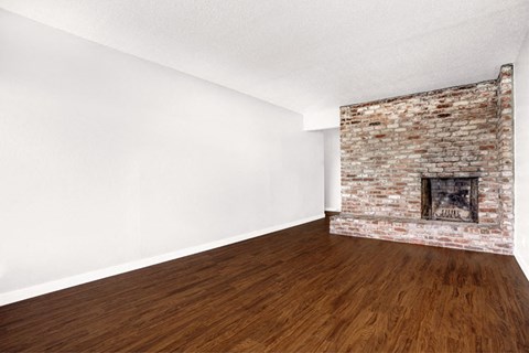 an empty room with a brick fireplace and wooden floors