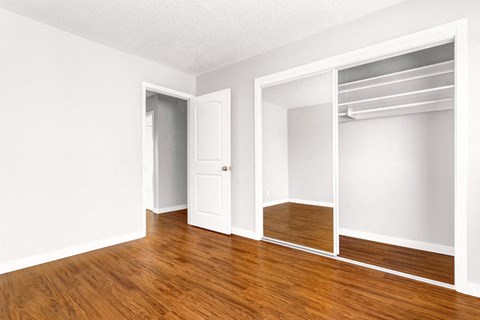 an empty room with white walls and wood floors and an open closet