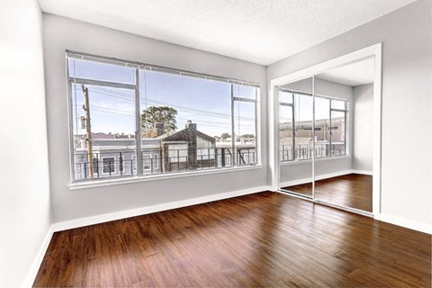 an empty living room with hard wood floors and large windows