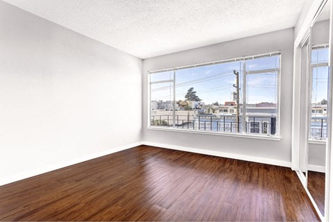 an empty living room with a large window and wood floors