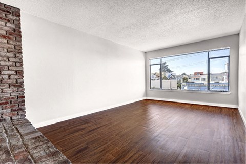 an empty living room with wood floors and a window
