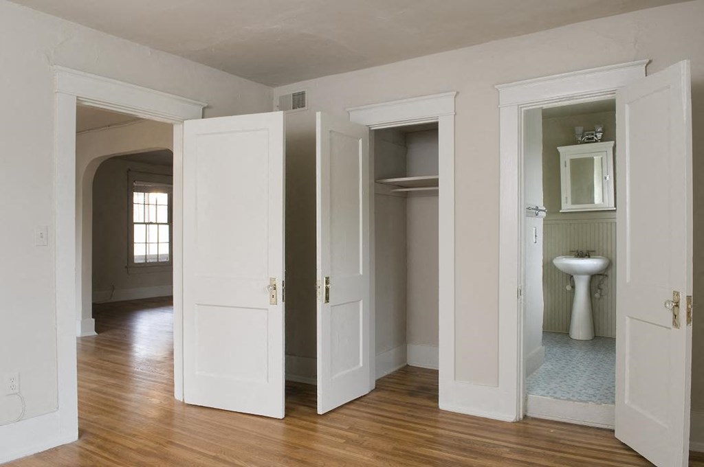 an empty room with five doors open and a toilet