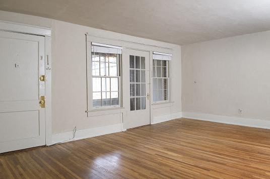 an empty living room with white walls and a wood floor