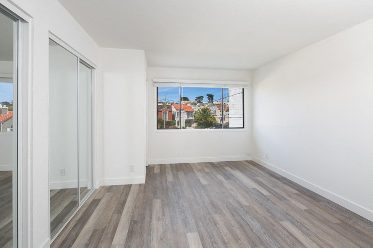 an empty living room with wood floors and a large window