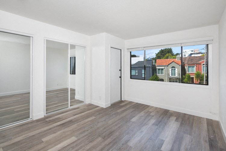 an empty living room with a large window and wooden floors
