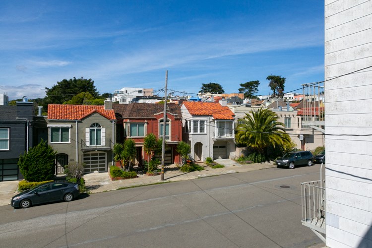 a view of a city street with houses and cars on a street