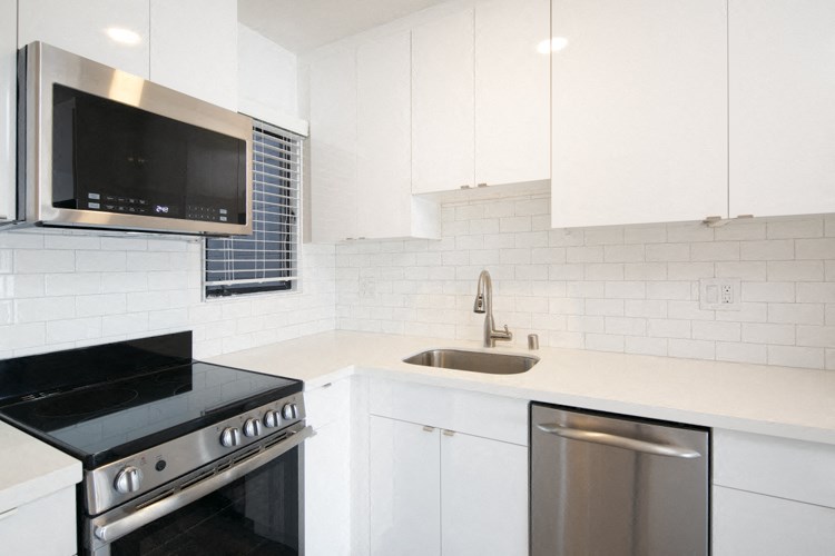 a kitchen with white cabinets and a stove and a sink