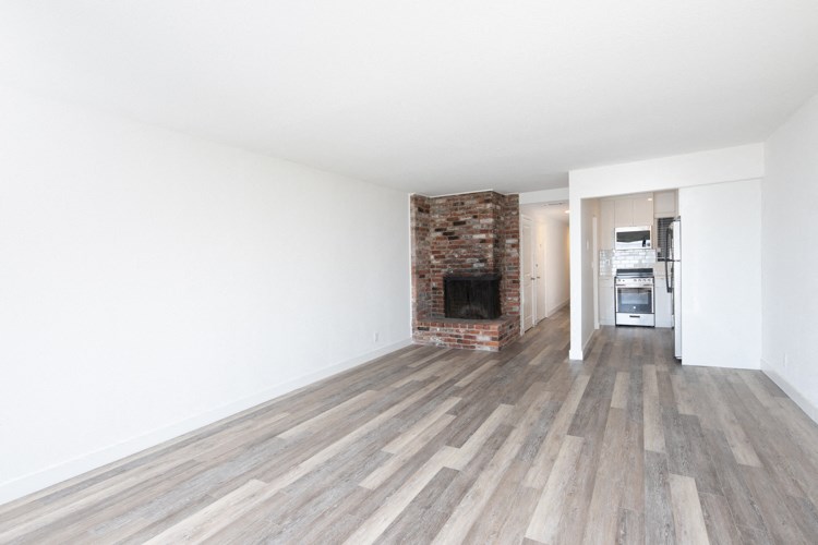 an empty living room with wooden floors and a brick fireplace