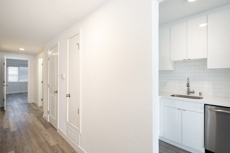 a white kitchen with white cabinets and white appliances and a wood floor