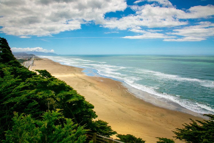 a view of a beach and the ocean from a cliff