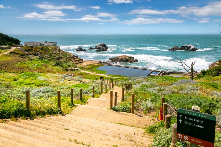 a set of stairs leading to the beach with the ocean in the background