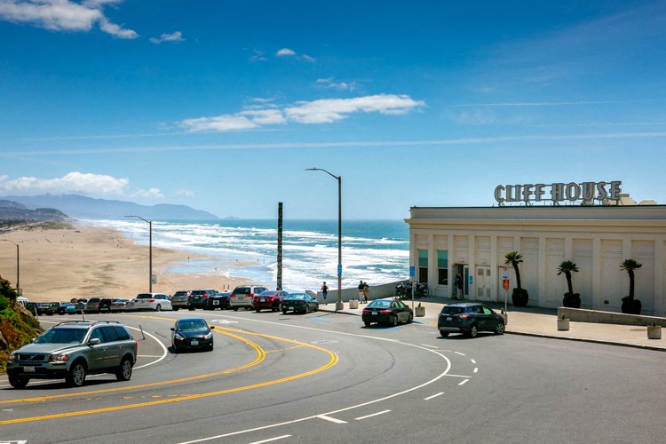 a city street with a building and the beach in the background