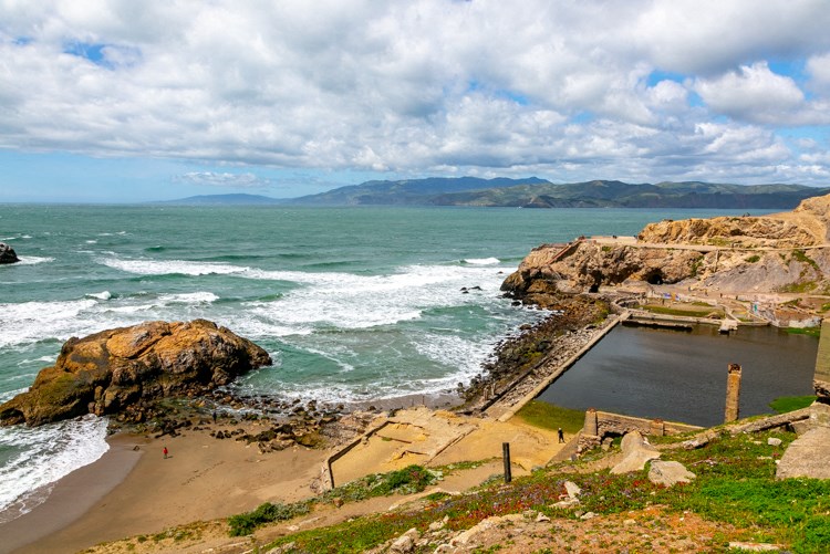 a beach with a pool next to the ocean