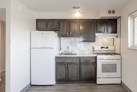A kitchen with white appliances and dark wood cabinets.