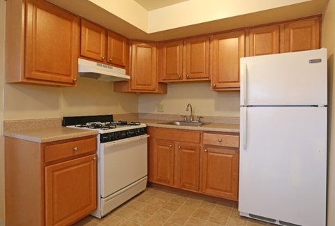 A kitchen with wooden cabinets and a white refrigerator.